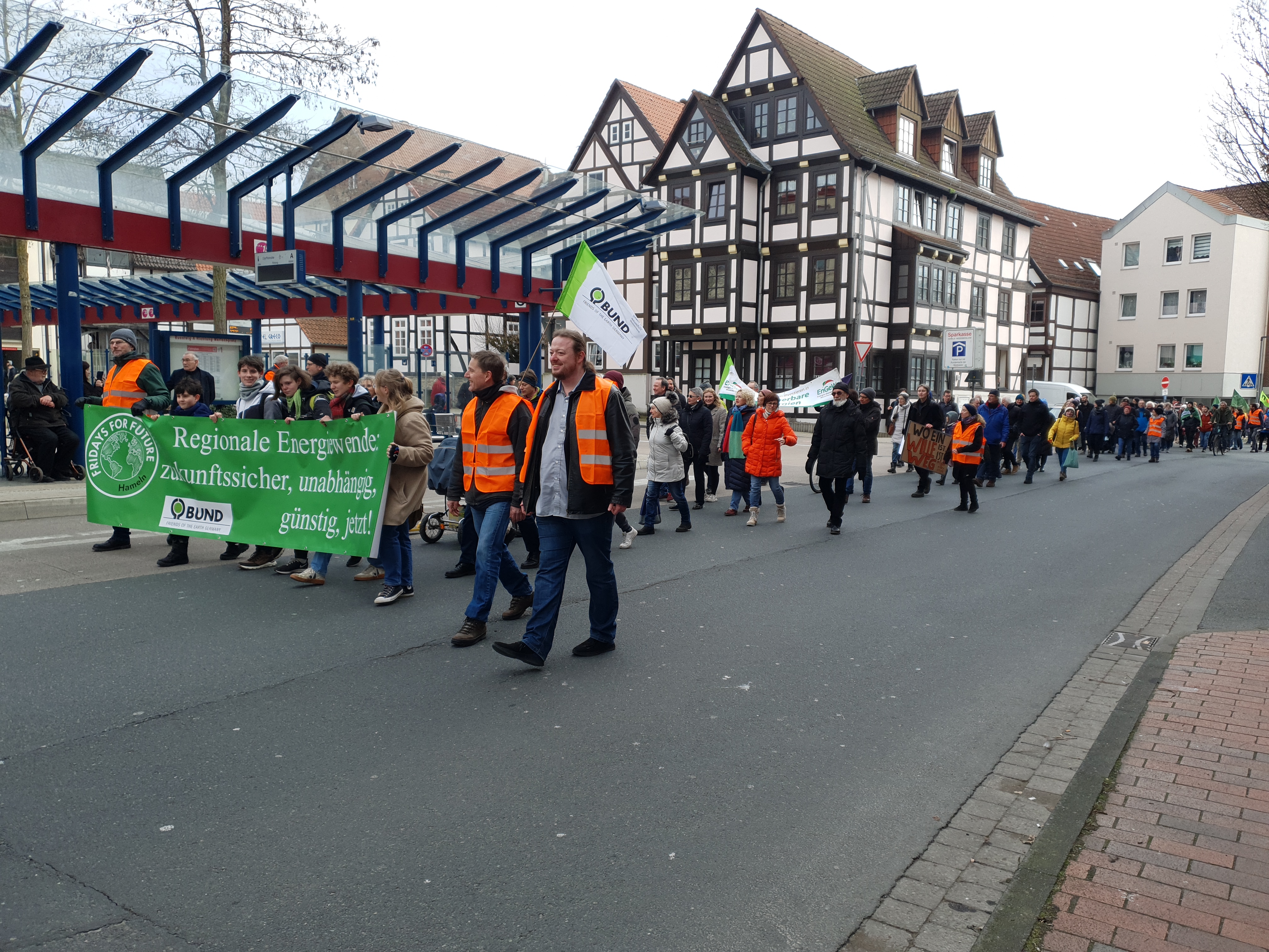 Demozug in Hameln vor dem ZOB. Die vorderste Reihe trägt ein Banner auf dem Steht: Regionale Energiewende zukunftssicher unabhängig günstig jetzt