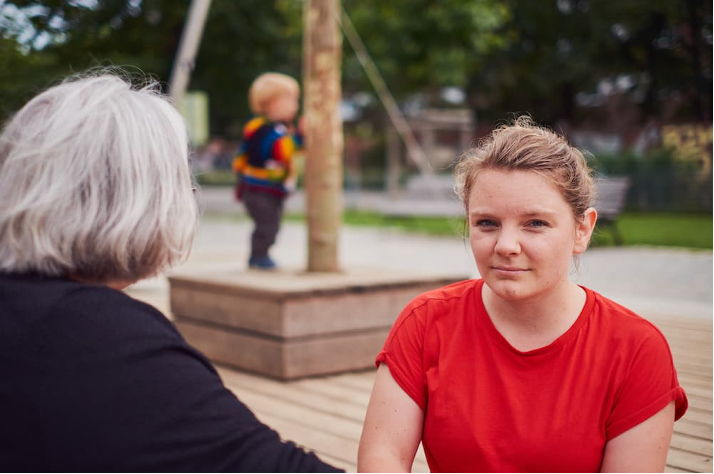 Zwei Menschen im Gespräch auf einem Spielplatz